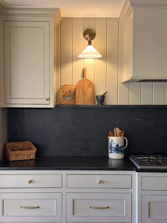 A honed black soapstone counter with a full slab backsplash and a stone shelf