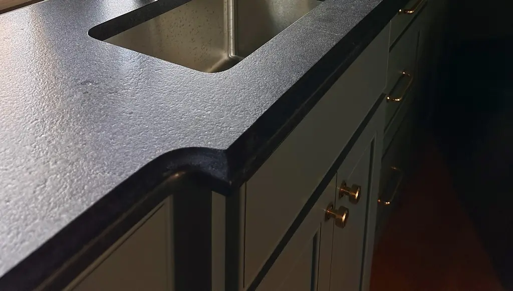 Honed black stone countertop with an undermount sink cut-out and a shaped corner edge