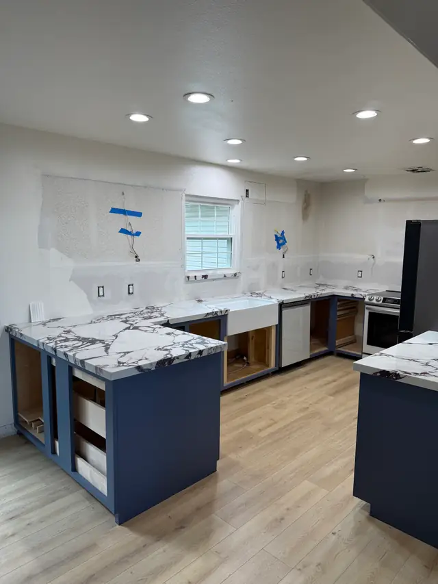 White marble with burgundy veining just set on navy cabinets, the walls still unfinished