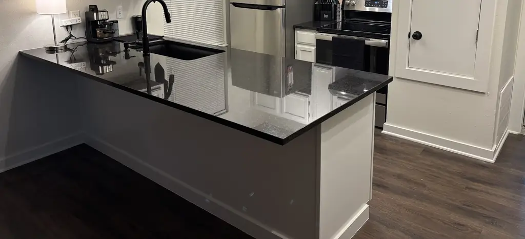 Polished black granite peninsula with an undermount sink in a white kitchen