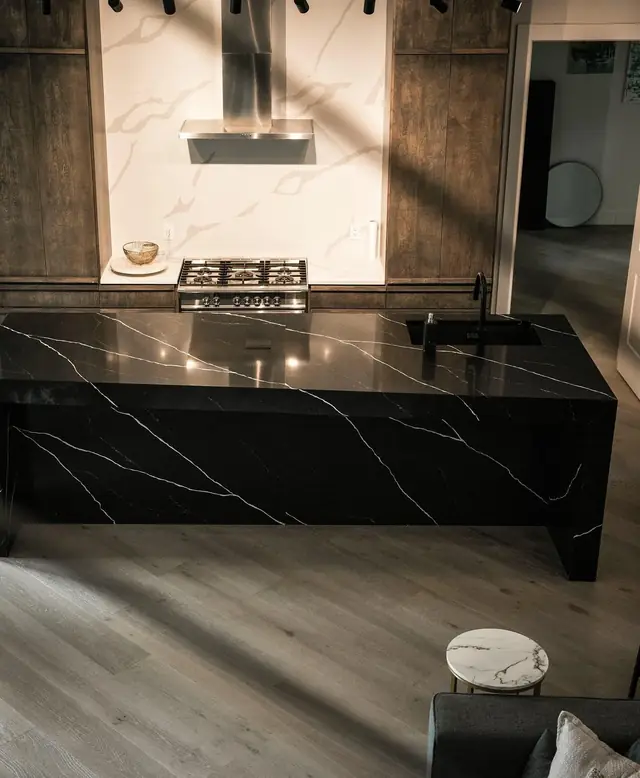 A black quartz waterfall island with white veining and walnut cabinets