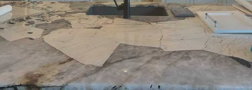 The top of a white and grey quartzite island, the veining running the length of the slab